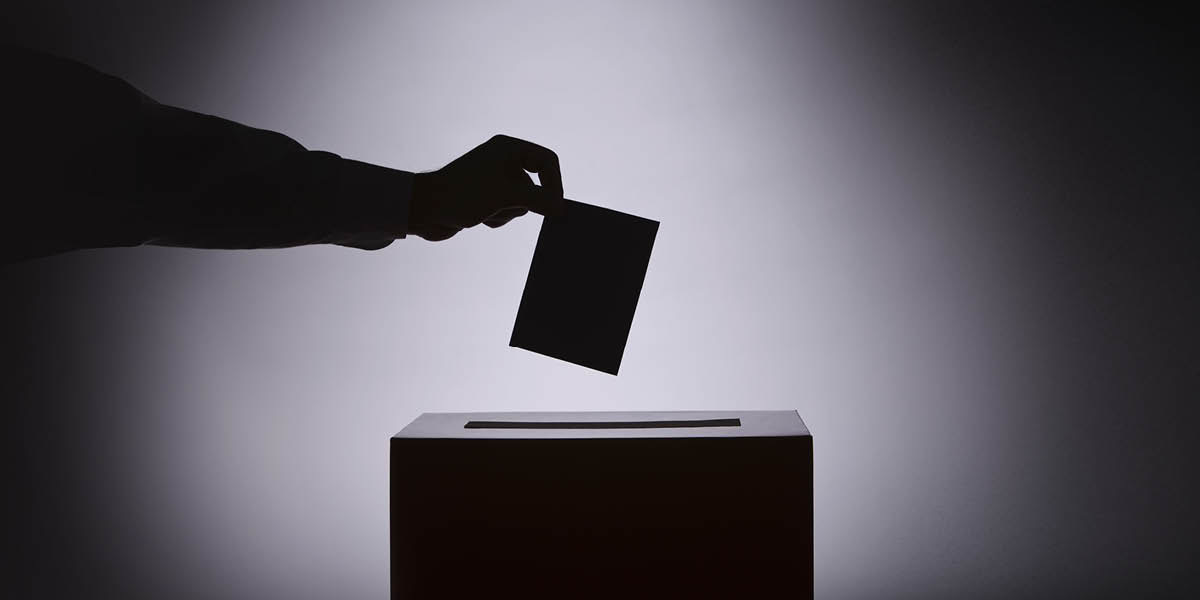 A vote being put into an election ballot box.