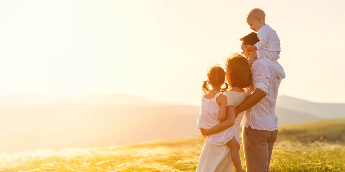 A happy family looking at the sun on the horizon.