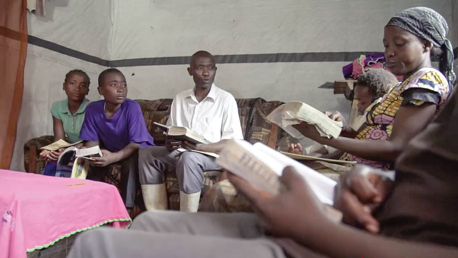 A scene from the video ‘Build a House That Will Endure​—Safeguard Your Children From ‘What Is Evil.’’ Parents in Africa read and discuss scriptures with their children.