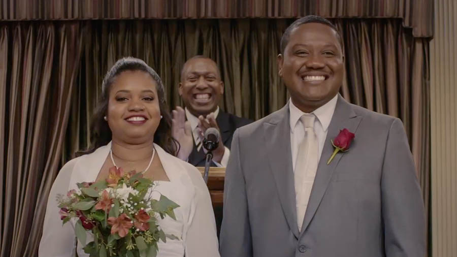 A scene from the video ‘We Must ‘Run With Endurance’​—Obey the Rules of the Contest.’ Brother and Sister Calou smile after their wedding talk at a Kingdom Hall.