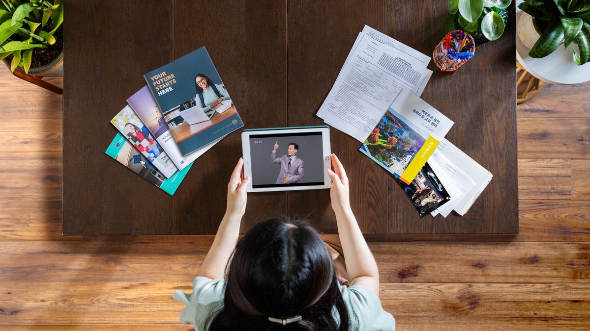 A young sister using a tablet to do research on possible future goals. To her left are brochures about secular education. To her right is an application for expanded theocratic service and information about Bethel.