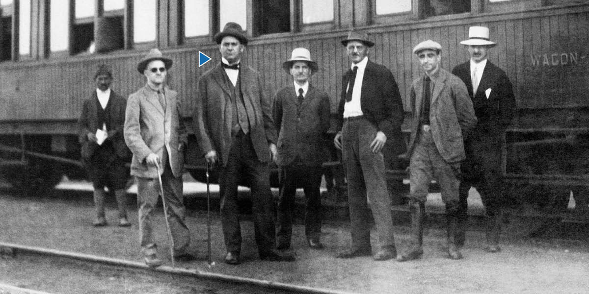 Joseph F. Rutherford and other brothers standing beside a train.