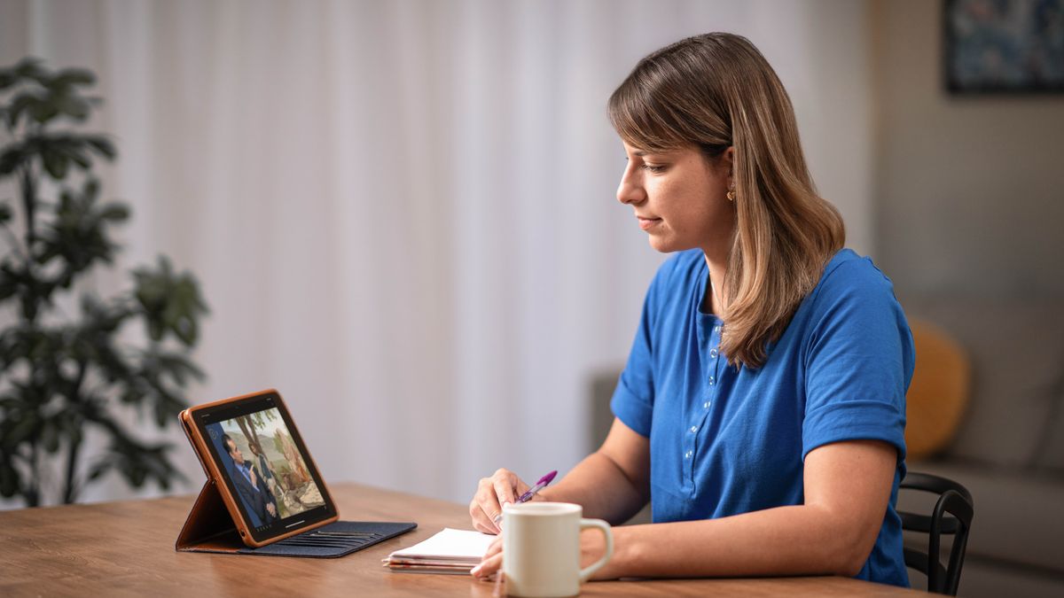 The sister in the previous image who was nervous and uncomfortable, now at home and reading the brochure “Love People​—Make Disciples.”