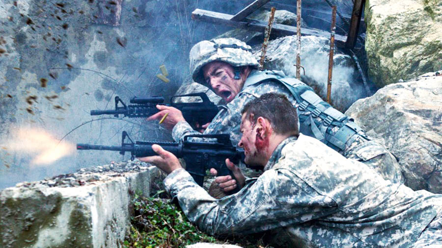 Soldiers in a battle, firing their rifles from behind a barricade.