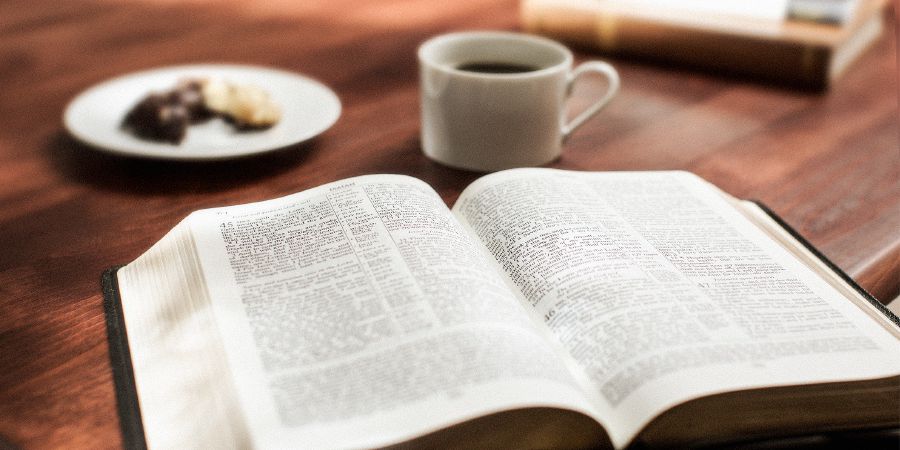 En uppslagen bibel med en kopp kaffe bredvid