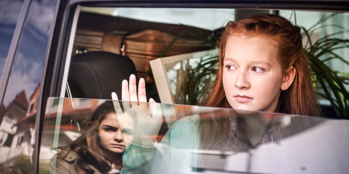 En ledsen tjej vinkar av en kompis som flyttar