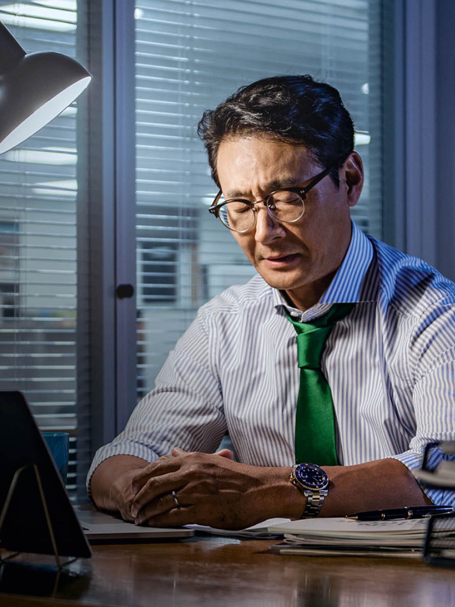 En affärsman sitter vid sitt skrivbord och ber.