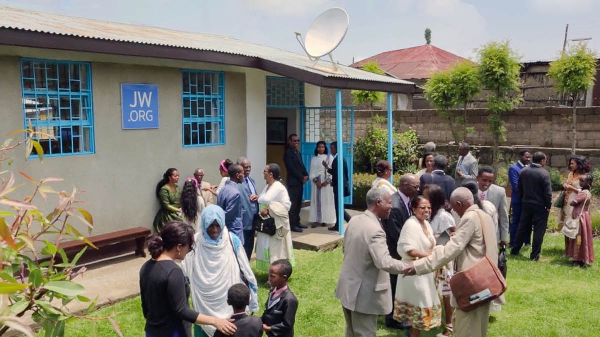 Brothers and sisters enjoying association with one another outside a Kingdom Hall.