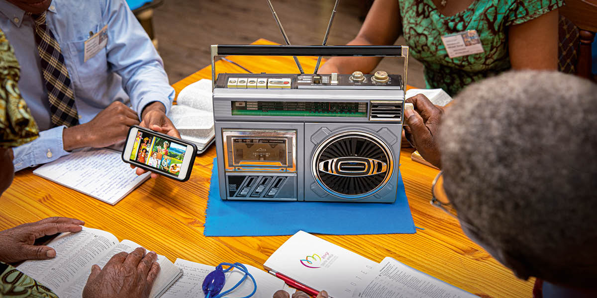 Bröder och systrar lyssnar på sammankomsten via radio.
