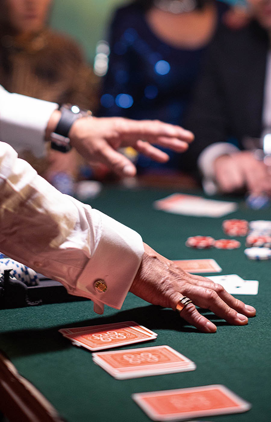 En man delar ut kort vid ett spelbord på ett kasino medan spelare ser på.