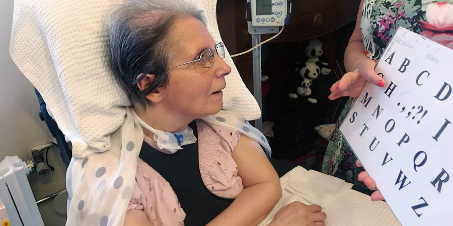 Virginia tittar på en tavla med bokstäver samtidigt som någon pekar på en bokstav.