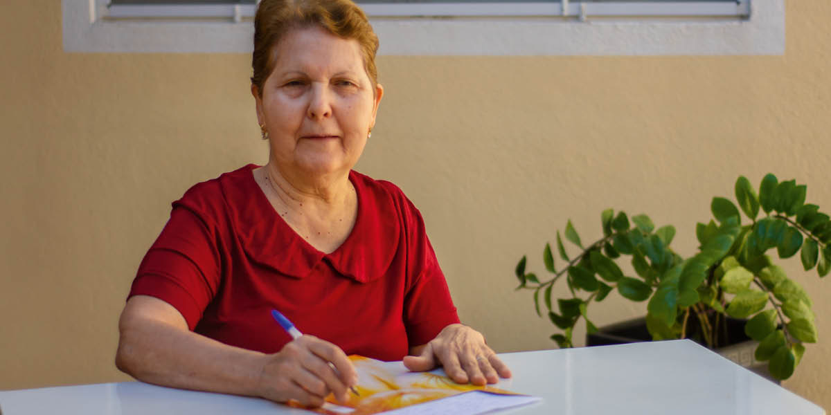 Maria Lúcia som skriver ett brev.