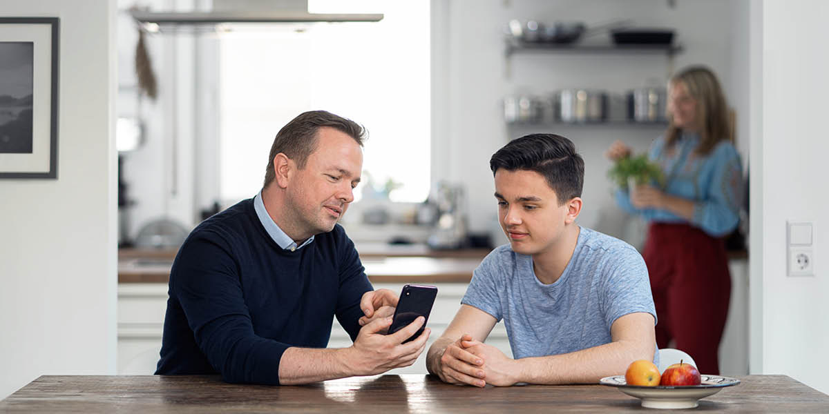 En pappa lär sin son att använda sin smartphone på ett bra sätt.