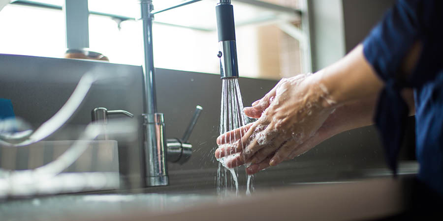 En kvinna tvättar händerna med tvål och vatten.
