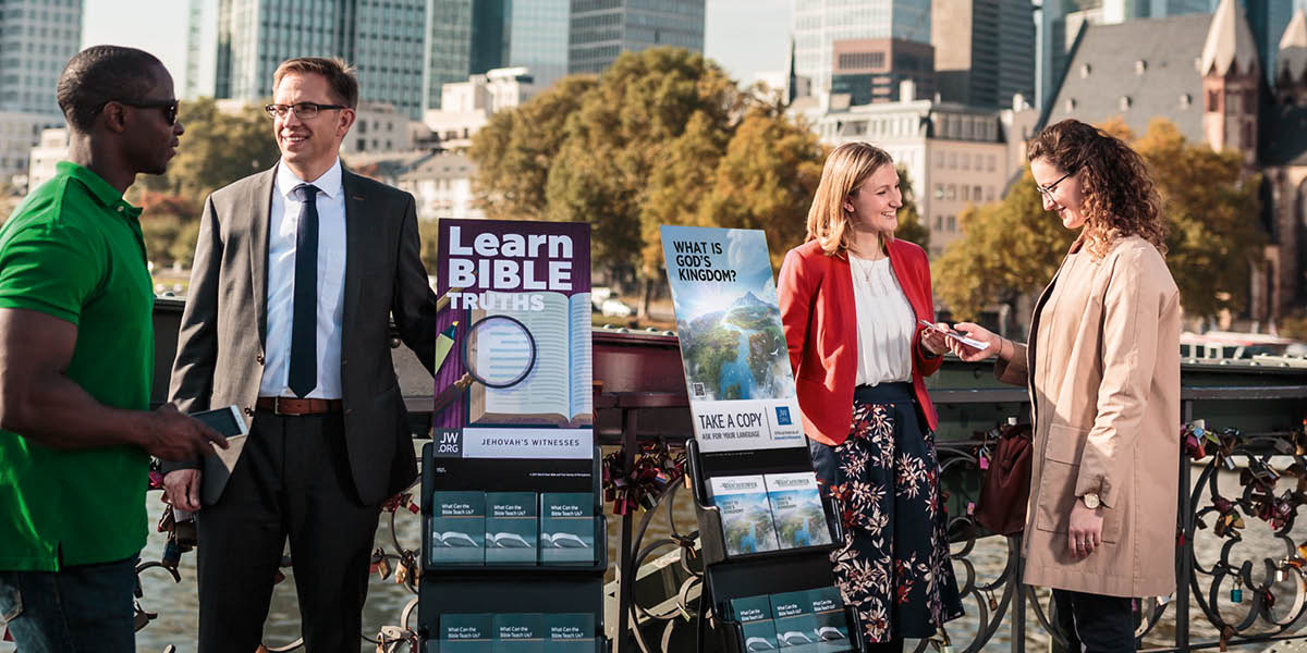En broder och syster gör vagntjänst och talar med människor. En litteraturvagn har en skylt som visar Vakttornet, nummer 2, 2020.