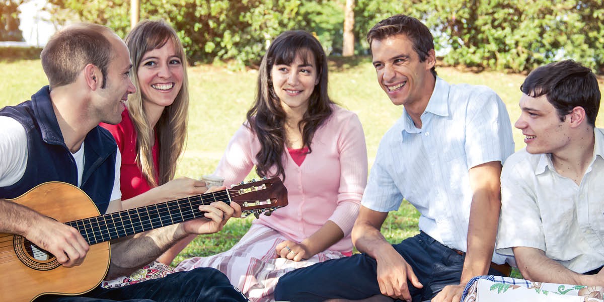Bröder och systrar spelar gitarr och sjunger tillsammans utomhus.