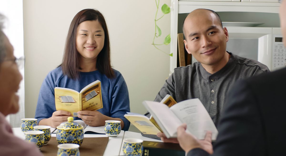 En scen ur videon ”Visa kärlek i församlingen – Mot invandrare”. Bill och Maggie Zeng sitter och ler under en bibelkurs.