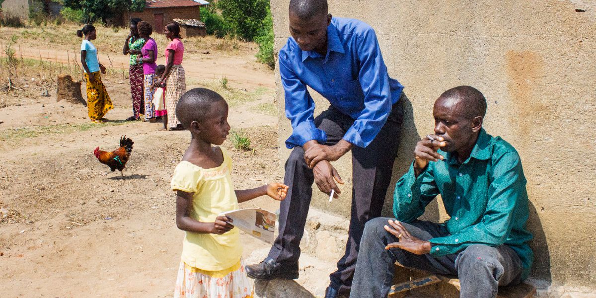 En liten flicka i Burundi visar Vakttornet för två män som ville ha några kolbitar