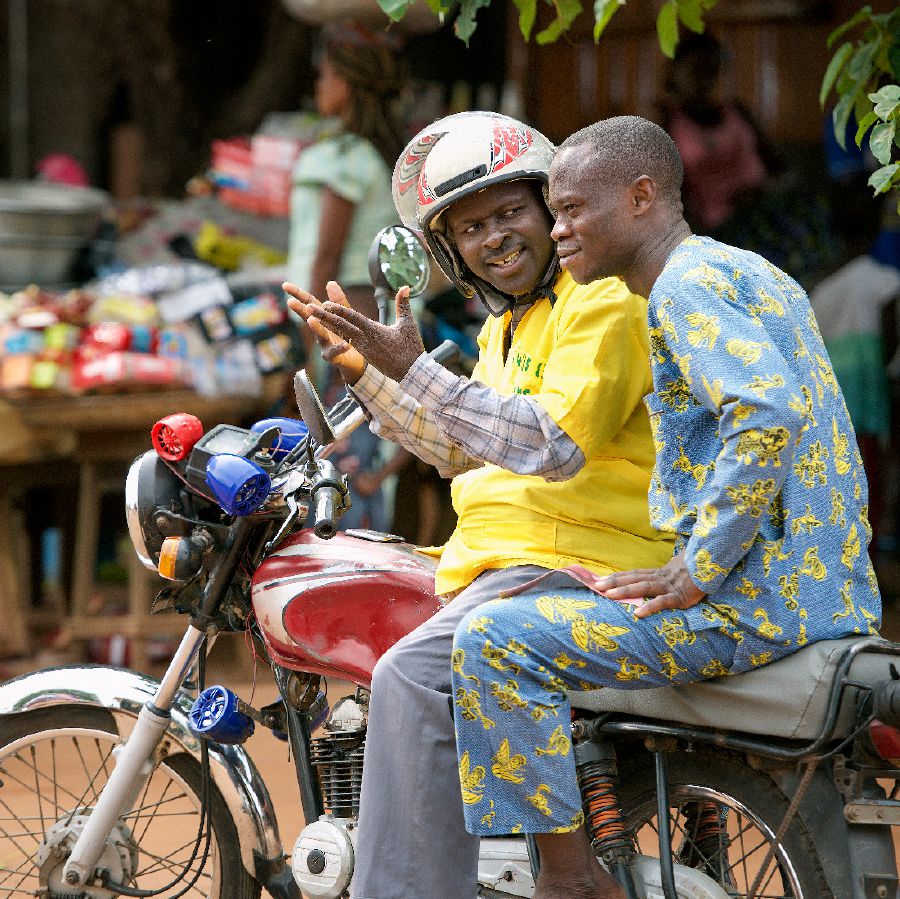 Désiré i Benin använder en musikspelare på sin motorcykeltaxi för att predika för en passagerare