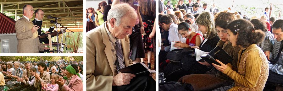 Åhörarna applåderar när Geoffrey Jackson presenterar den nya upplagan av Nya världens översättning på georgiska. Vittnen bläddrar i sina nya biblar.