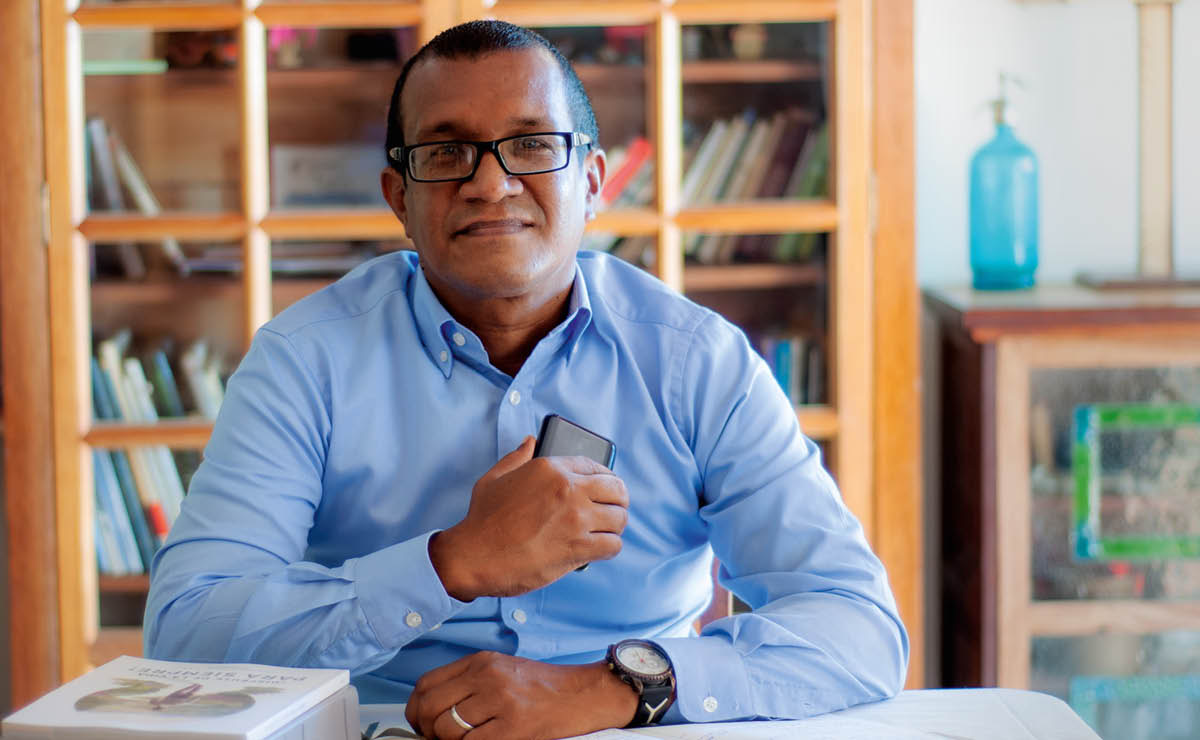Argenis akiwa na simu, Biblia, na kitabu “Furahia Maisha Milele!” mezani