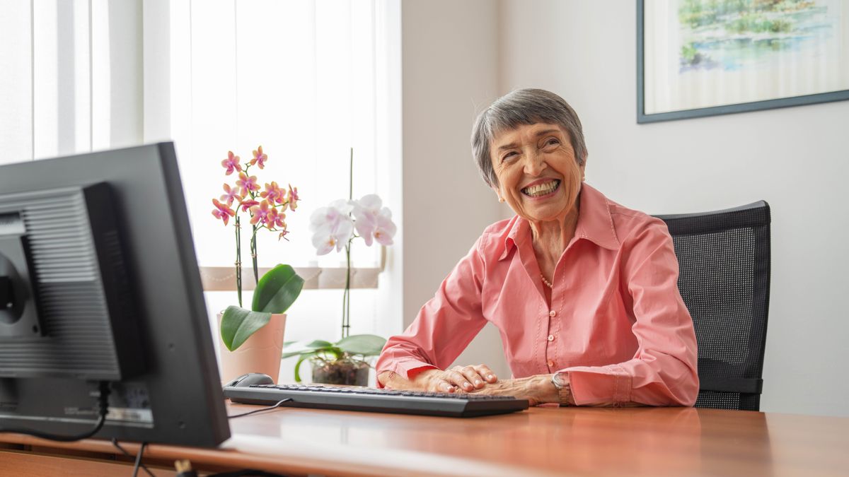 Irma happily sitting at a computer in her office.