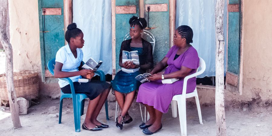 Gérole na binti yake wakimfundisha Biblia msichana mdogo nchini Haiti