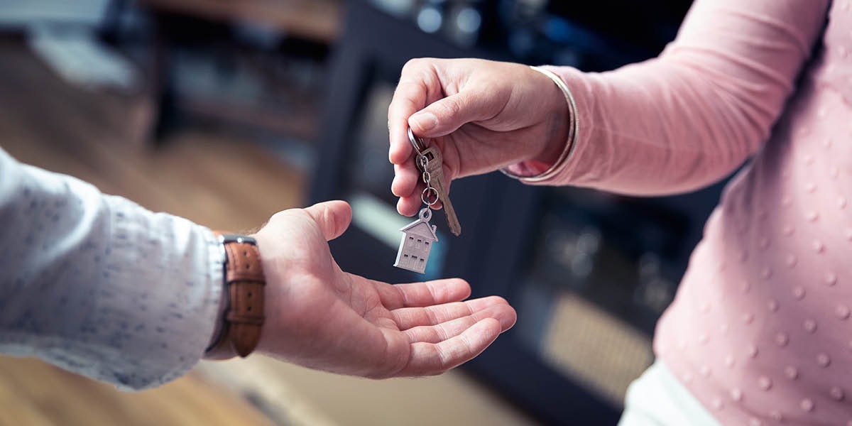 A woman giving her house key to a man.