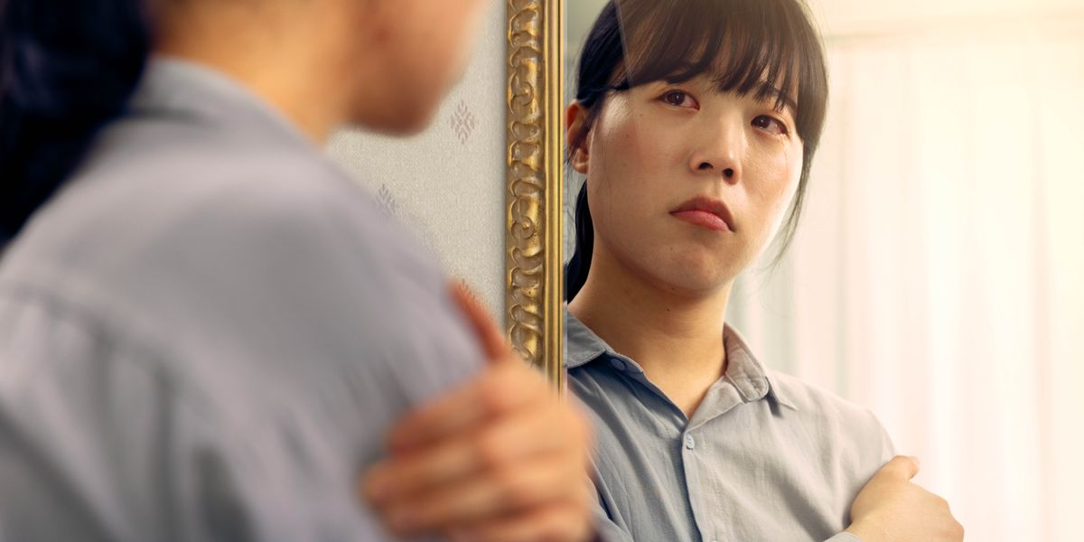 ผู้​หญิง​คน​หนึ่ง​ที่​กำลัง​เศร้า​มอง​ดู​ตัว​เอง​ใน​กระจก