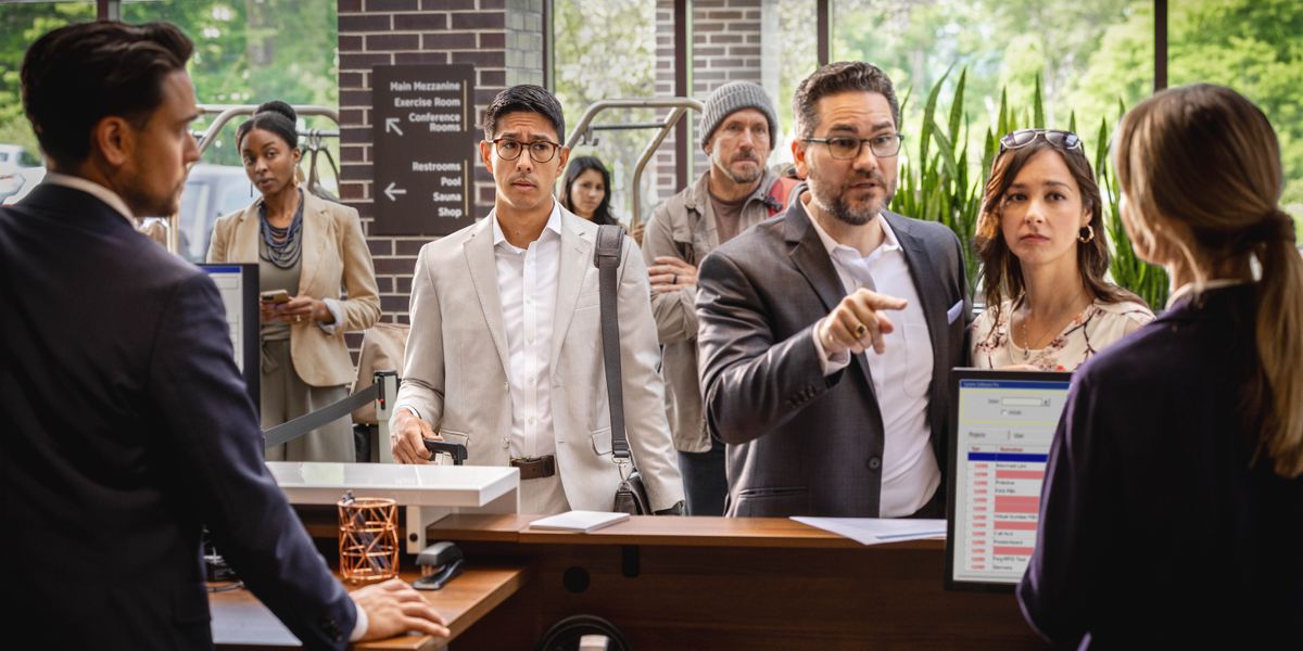 ผู้​ชาย​คน​หนึ่ง​ที่​อารมณ์​เสีย​กำลัง​พูด​ไม่​ดี​กับ​เจ้าหน้าที่​ต้อนรับ​ของ​โรงแรม มี​ลูกค้า​อีก​หลาย​คน​เข้า​คิว​ต่อ​จาก​เขา