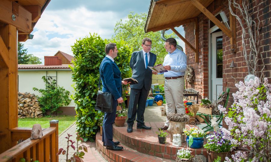 เบอร์นฮาร์ด เมอร์เทน​กับ​พยาน​พระ​ยะโฮวา​อีก​คน​หนึ่ง​ยืน​ประกาศ​ที่​หน้า​ประตู​บ้าน