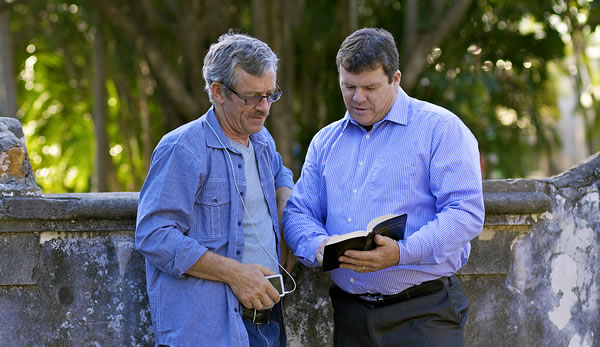 Ian King reading a verse from the Bible to a man.