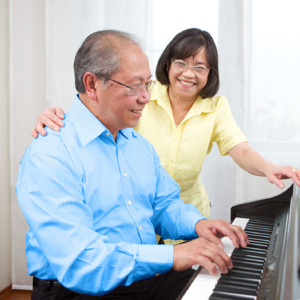 Wanpela lapun man i amamas long pilaim piano long meri bilong en