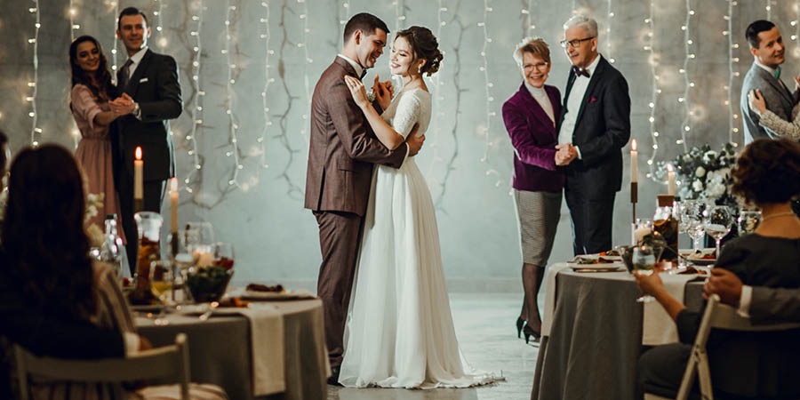 A bride and groom dancing at their wedding reception along with some of their guests.
