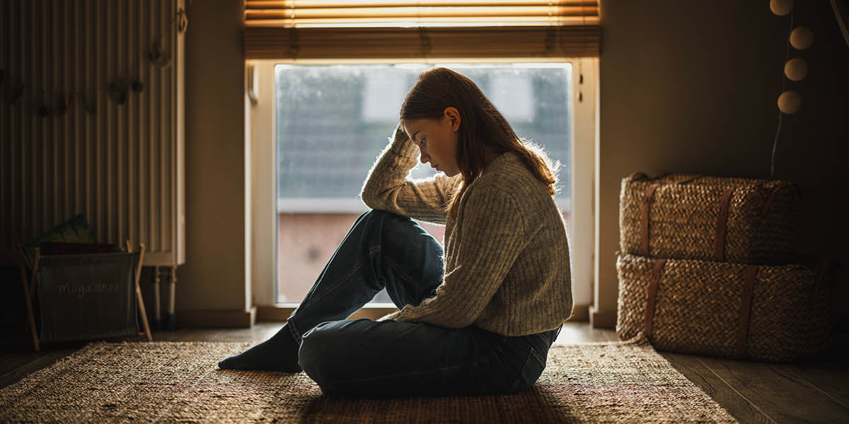 An adolescent girl staring hopelessly at the floor.