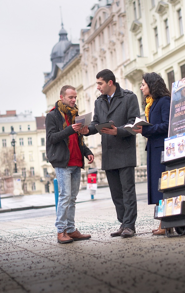 Jehovah’s Witnesses in a metropolitan area share Bible information with a man