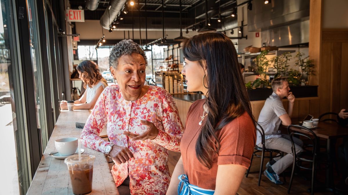 Молода і літня сестра спілкуються в кафе; молода уважно слухає літню.