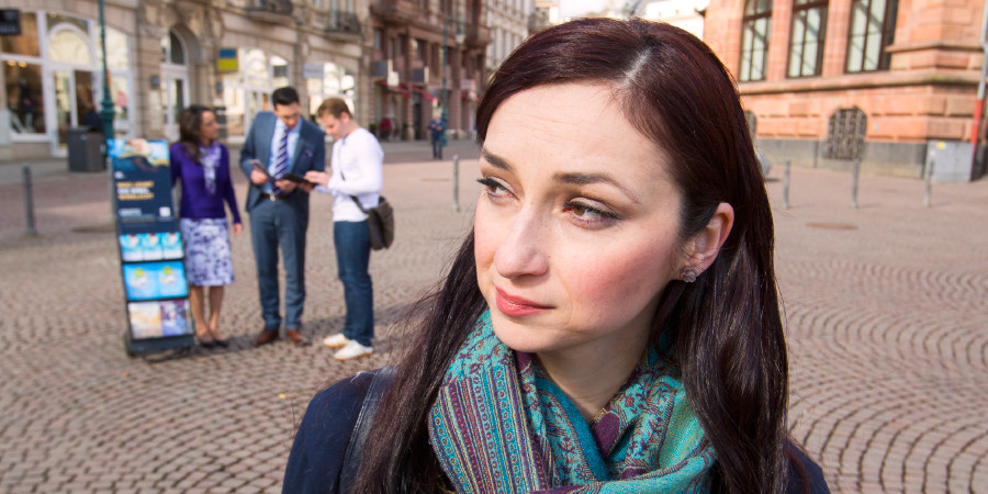 Жінка спостерігає за Свідками Єгови, які проповідують за допомогою пересувного стенда з літературою