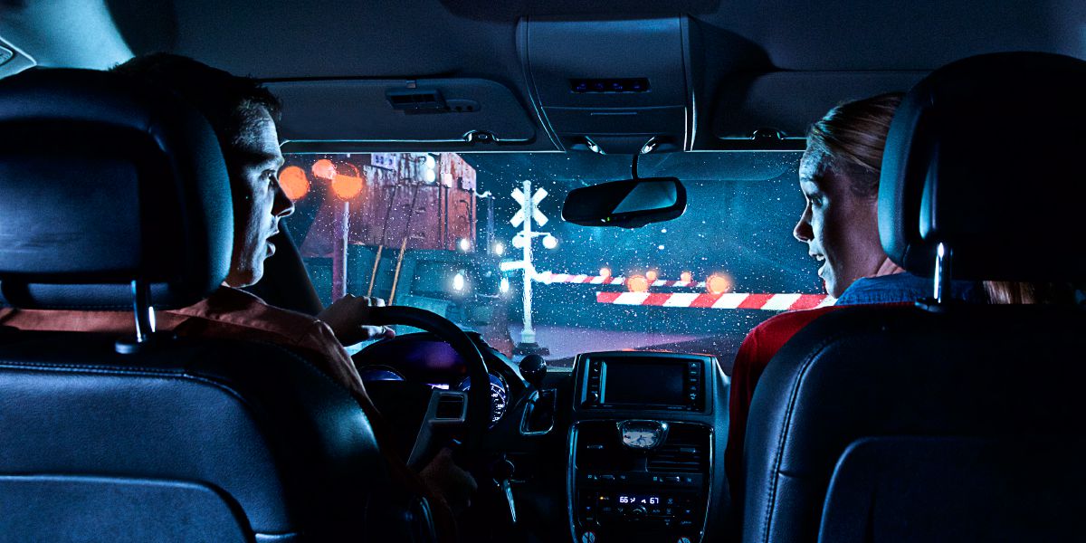 Пара сидить в автомобілі перед залізничним переїздом