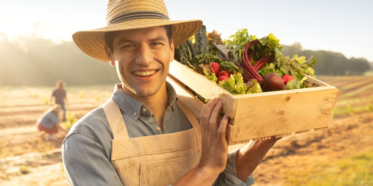 Un colono contento el porta nele spale una cassa de verdure.