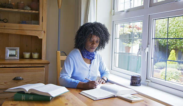 Chị Rosalind John đang ghi chú và dùng các ấn phẩm tra cứu khi học hỏi Kinh Thánh cá nhân.