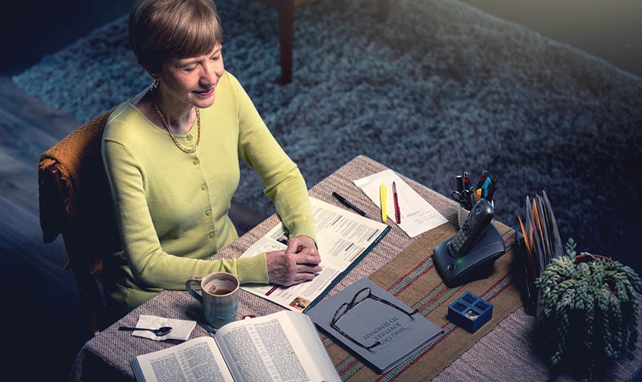 Một chị nghe chương trình nhóm họp qua điện thoại cúi đầu khi lời cầu nguyện được dâng