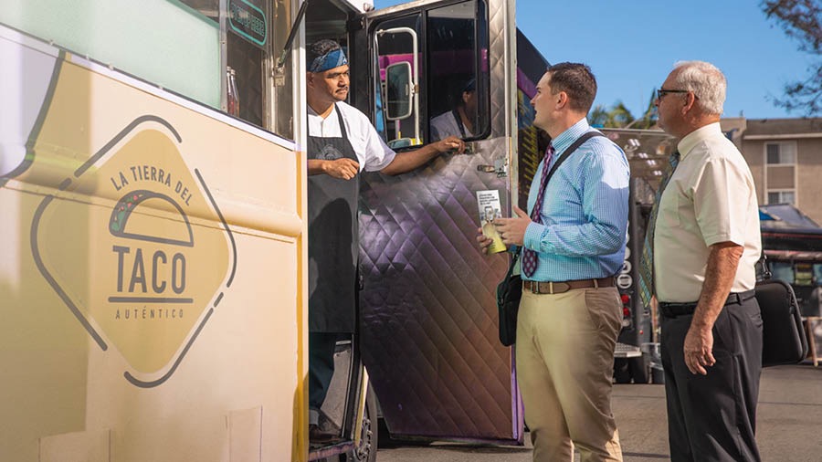 Một anh đang giới thiệu tờ chuyên đề cho đầu bếp trong xe bán thức ăn.