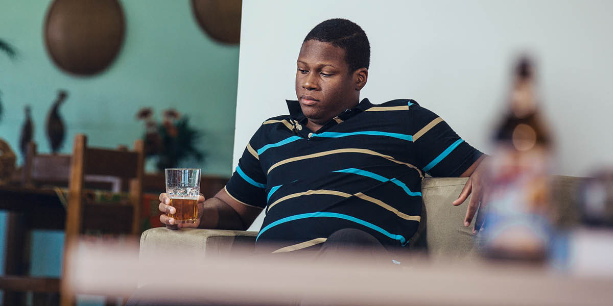 One woman dey alone for e house, e sitdown and de look wine wey dey inside glass cup.