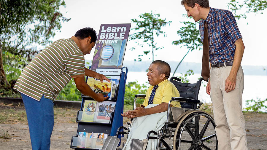 Mark Herman sit-down for wheelchair near one magazine-stand, e de preach to one man.