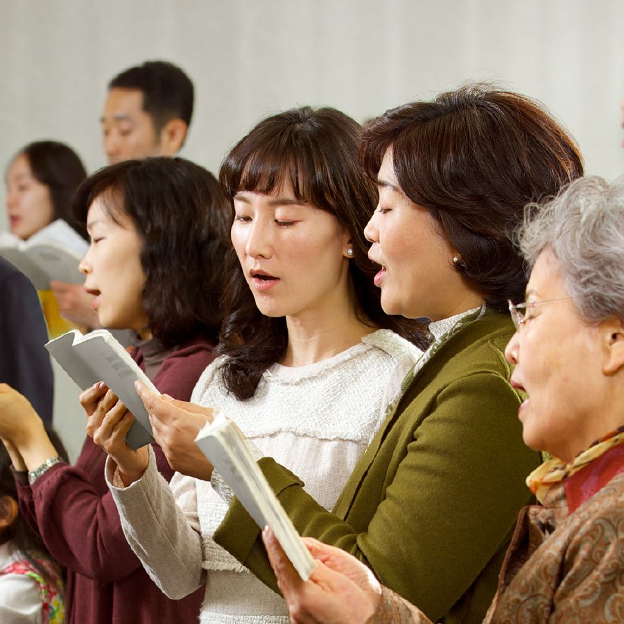 Àwọn arábìnrin méjì ń pín ìwé orin kan lò bí wọ́n ṣe ń kọrin