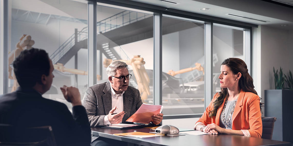 两位男士在面试一位想在汽车工厂上班的女子，这位女子的神情有点紧张