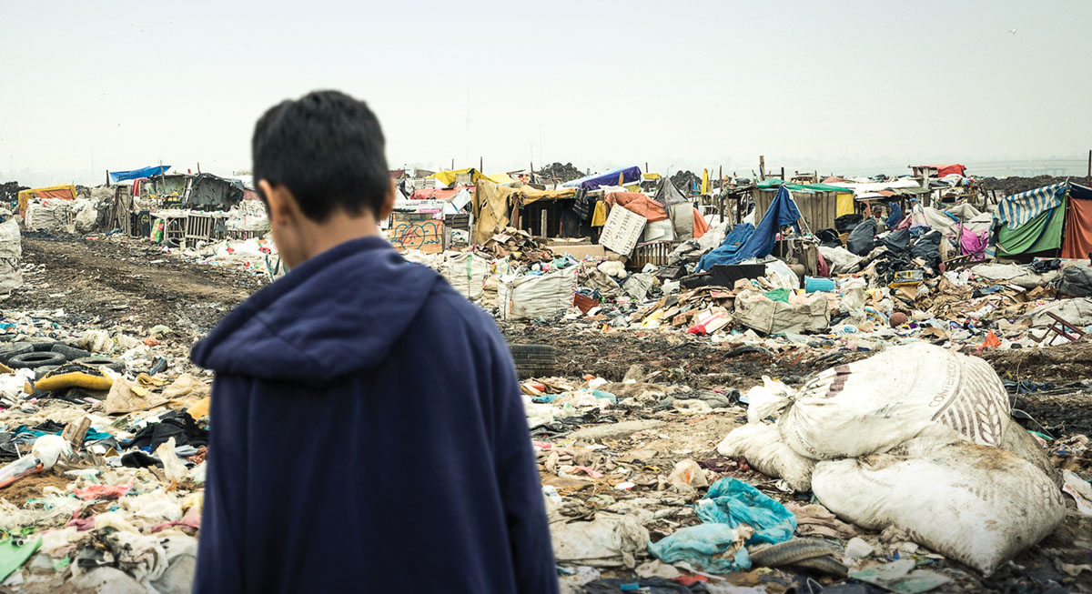 一个男孩站在垃圾堆中；伊斯雷尔·马丁内斯曾住在垃圾堆里三年