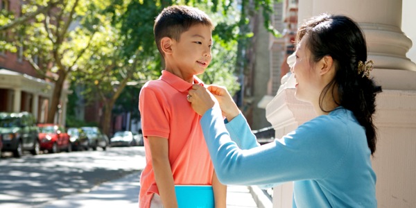 一个母亲帮她年幼的儿子扣好衬衫的扣子