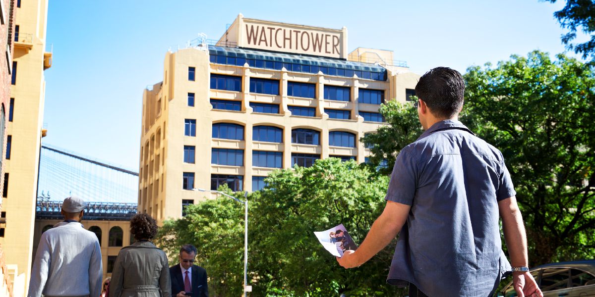 男子手中拿着圣经特展的邀请单，前往纽约布鲁克林哥伦比亚山道25号的伯特利